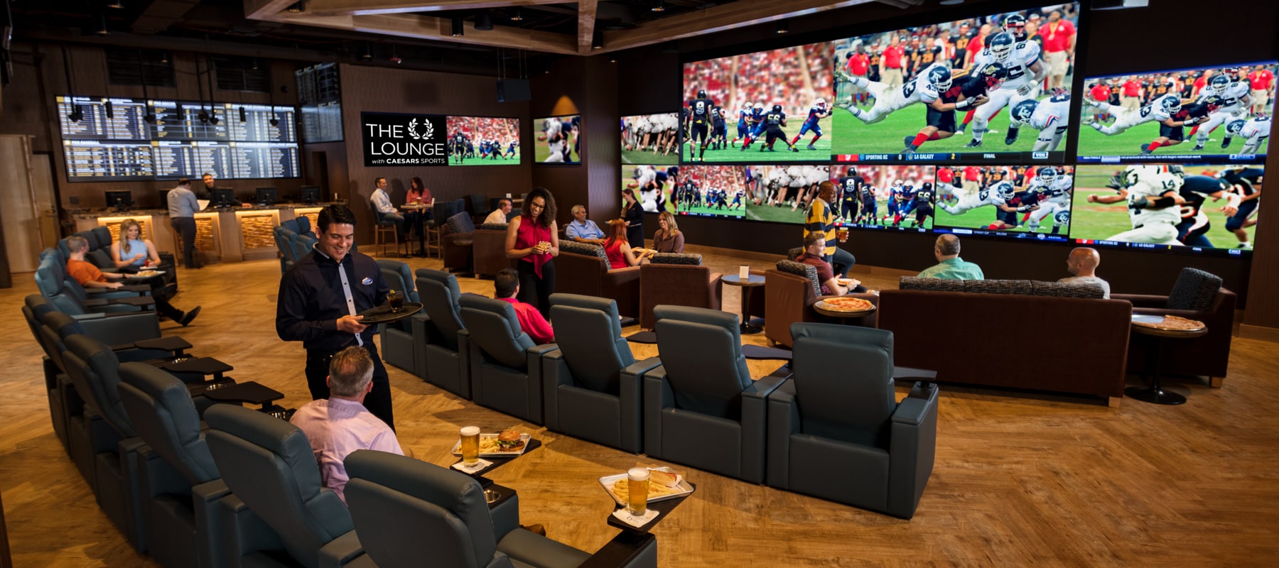 wide shot: Fans enjoy beer and burgers at the Lounge Sports Book at Point Place Casino