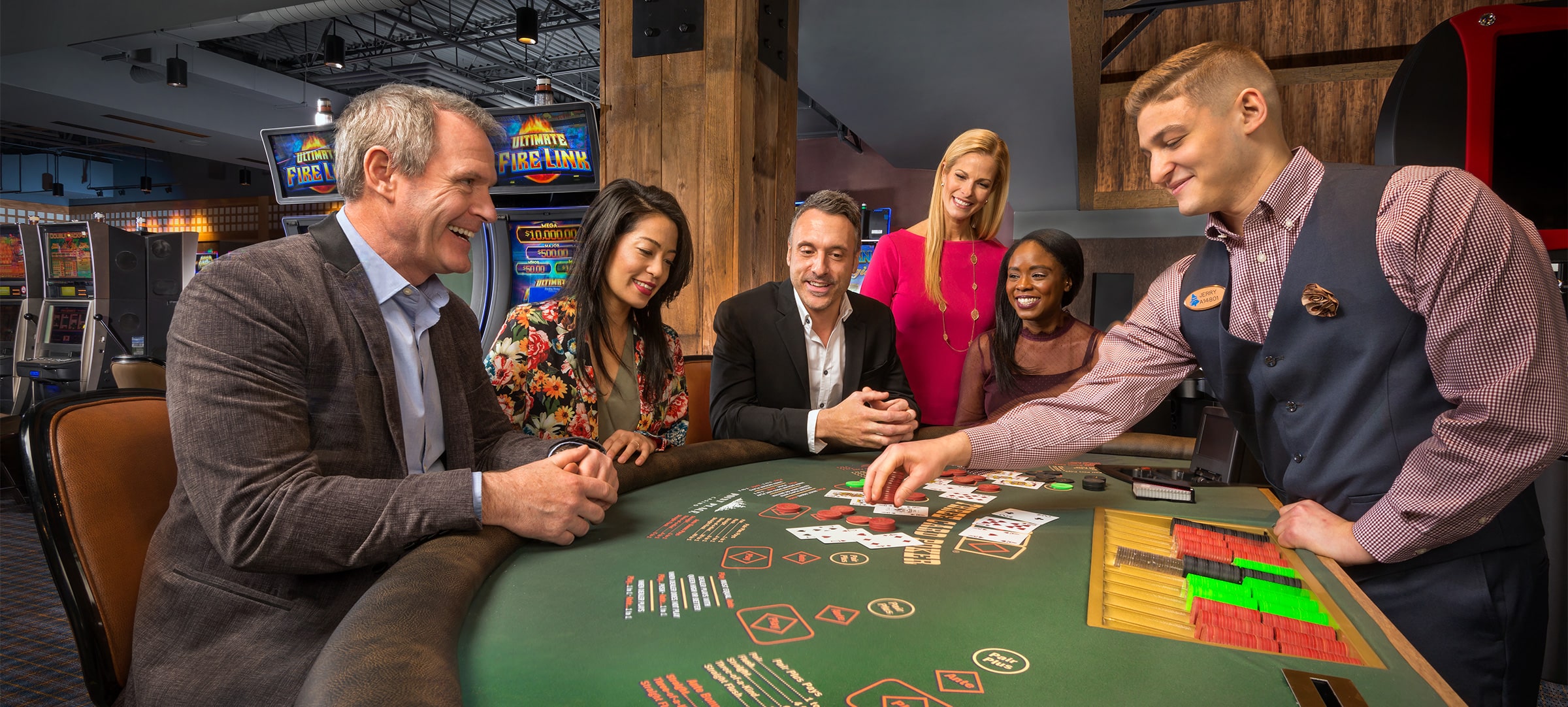 A crowd plays blackjack at Point Place Casino in front of the Ultimate Fire Link Slot Machine